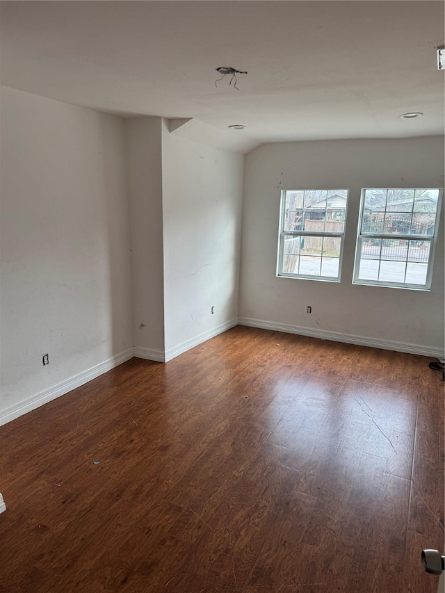 spare room with baseboards and wood finished floors