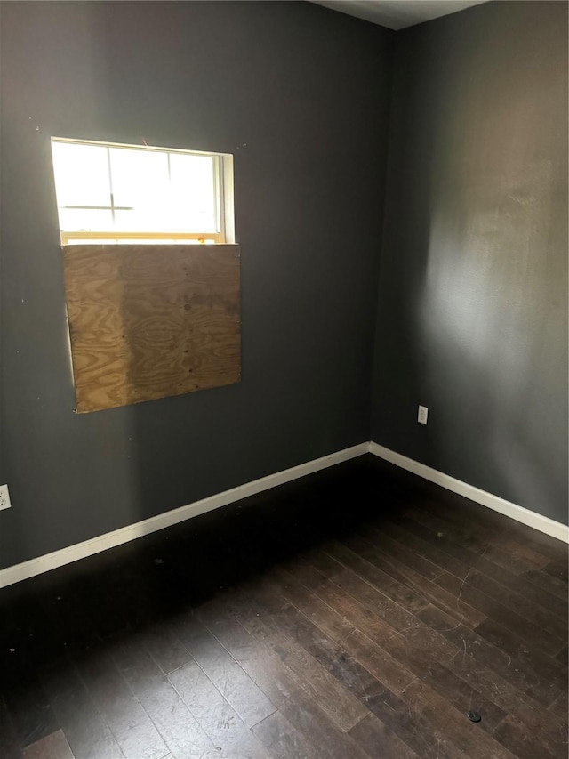 spare room with baseboards and wood finished floors