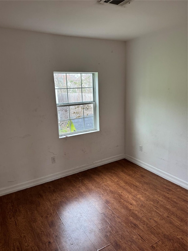 empty room featuring visible vents, baseboards, and wood finished floors