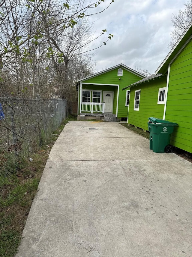 exterior space featuring driveway, covered porch, and fence