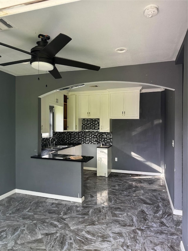 kitchen with dark countertops, marble finish floor, a peninsula, and a ceiling fan