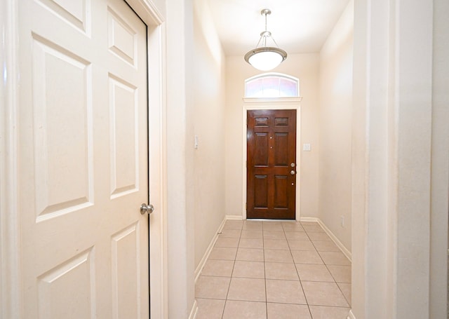 doorway with light tile patterned flooring and baseboards