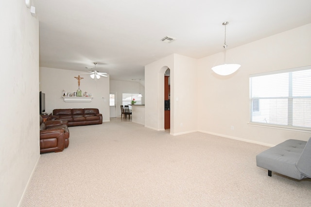 living room with arched walkways, visible vents, light carpet, and baseboards