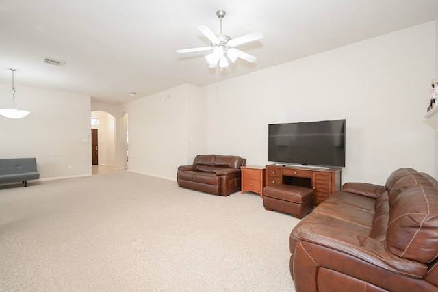 living area with light carpet, baseboards, visible vents, arched walkways, and a ceiling fan