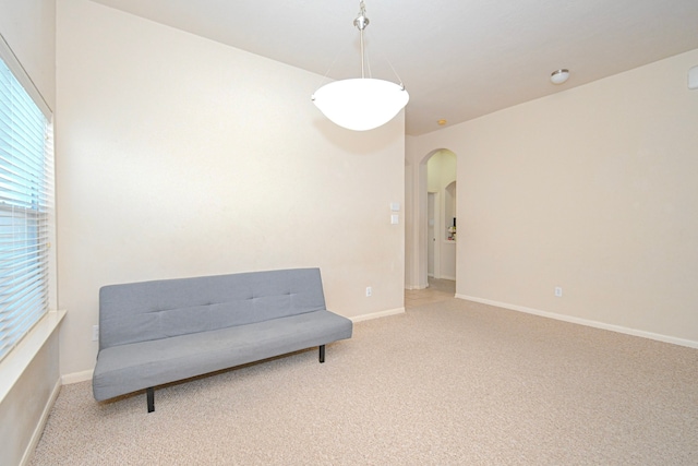 sitting room with baseboards, plenty of natural light, arched walkways, and carpet flooring