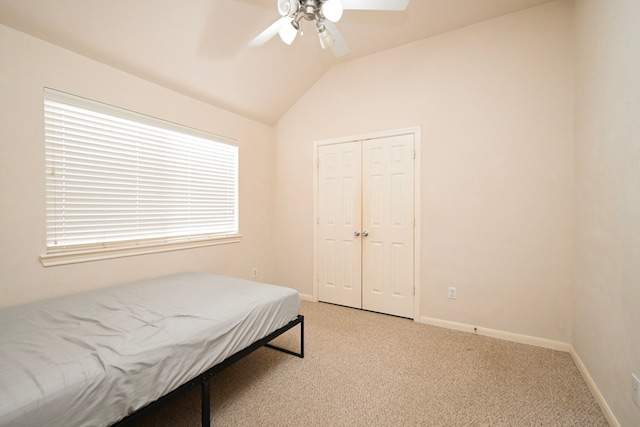 bedroom featuring a closet, light carpet, vaulted ceiling, ceiling fan, and baseboards