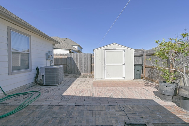 view of patio / terrace with an outbuilding, central AC, a fenced backyard, and a shed