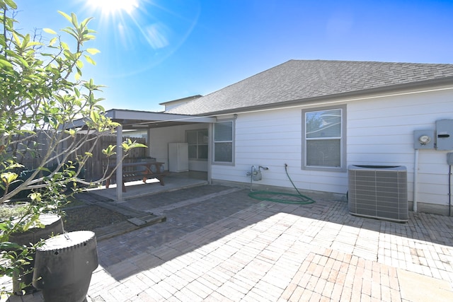 back of house featuring a shingled roof, fence, cooling unit, and a patio