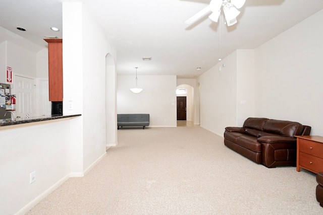 sitting room with ceiling fan, visible vents, arched walkways, and light colored carpet