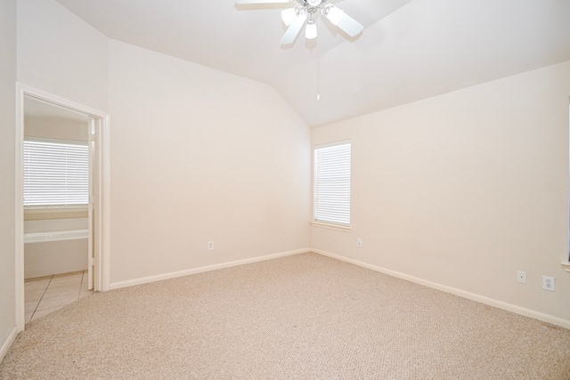 unfurnished room with baseboards, vaulted ceiling, a ceiling fan, and light colored carpet