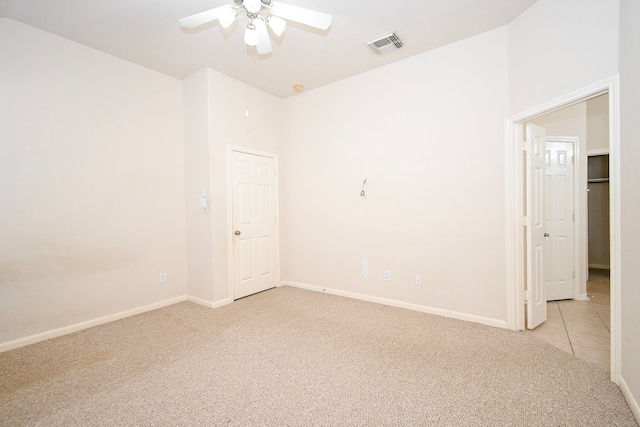 empty room with light tile patterned floors, light carpet, visible vents, baseboards, and a ceiling fan