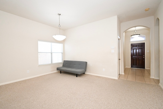 unfurnished room featuring baseboards, arched walkways, and light colored carpet