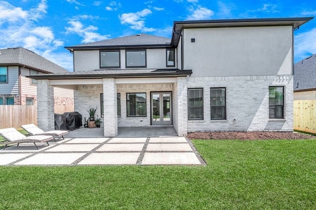 rear view of house featuring brick siding, a patio, stucco siding, a lawn, and fence