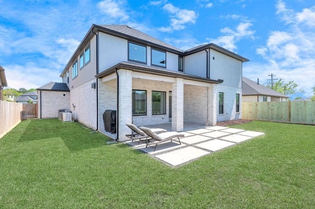 back of property with brick siding, a patio, a fenced backyard, and a lawn