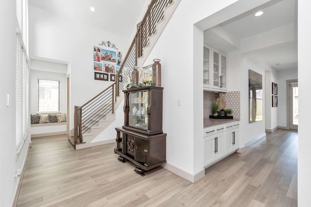 interior space with light wood-style floors, baseboards, and stairway