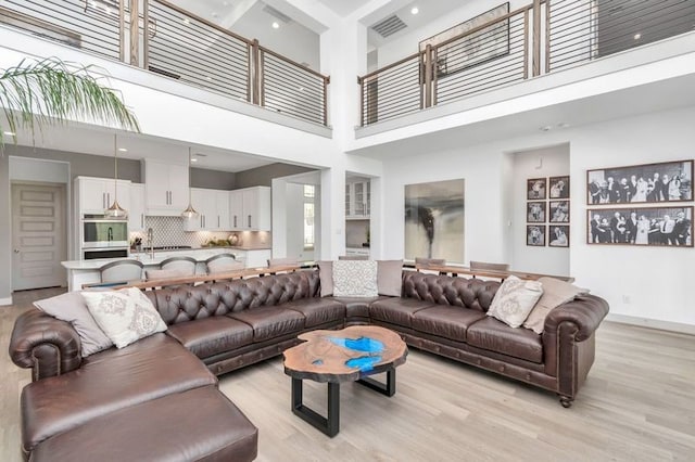 living room with light wood-style flooring, visible vents, and baseboards