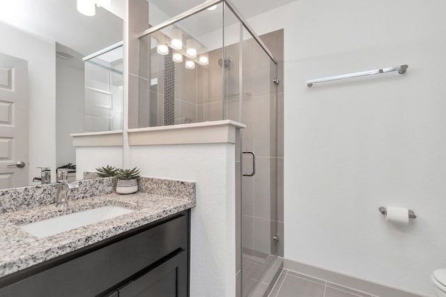 bathroom featuring tile patterned flooring, toilet, a shower stall, and vanity