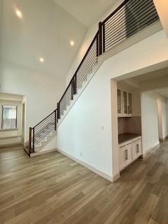 interior space with dark wood-style flooring, recessed lighting, stairway, a towering ceiling, and baseboards