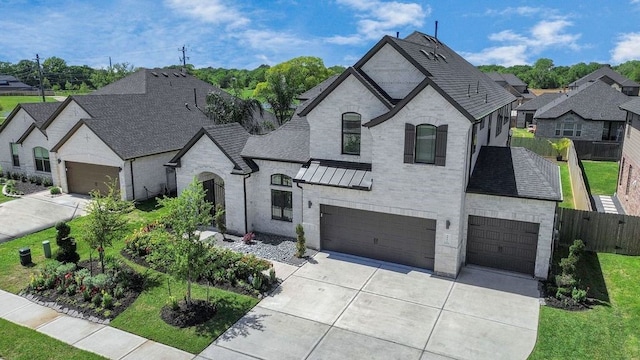 french country home featuring roof with shingles, brick siding, a standing seam roof, fence, and driveway