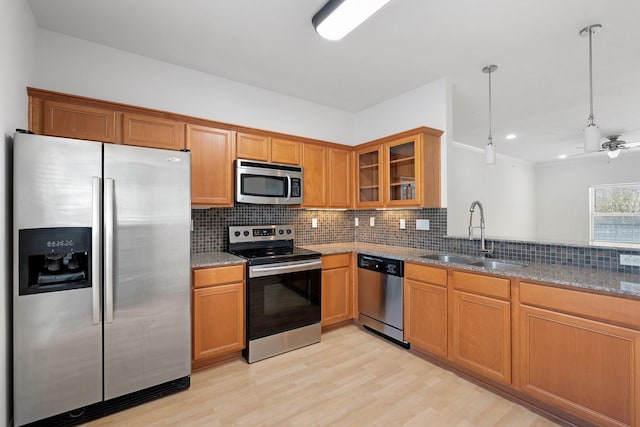 kitchen with light stone countertops, decorative backsplash, stainless steel appliances, and a sink