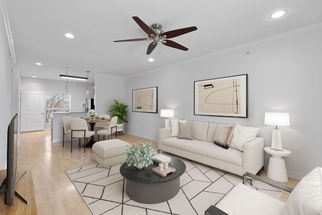 living room with light wood finished floors, ornamental molding, and recessed lighting