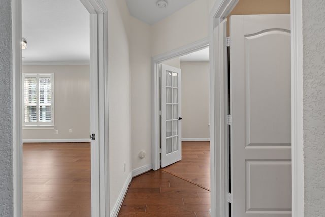 hall featuring baseboards, wood finished floors, and crown molding