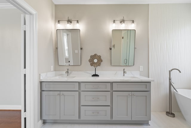 full bathroom featuring double vanity, a freestanding tub, and a sink