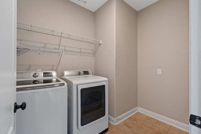 laundry room with visible vents, washing machine and dryer, light tile patterned floors, baseboards, and laundry area