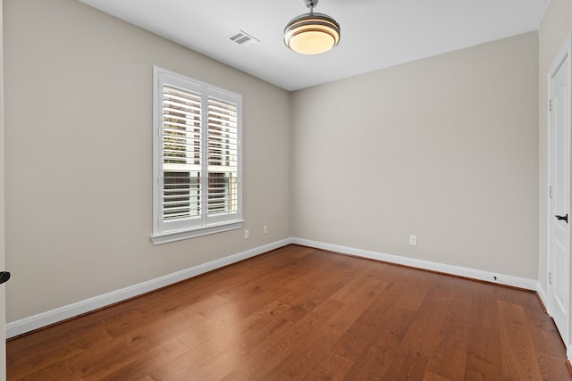 unfurnished room with wood finished floors, visible vents, and baseboards