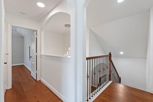 corridor with baseboards, lofted ceiling, an upstairs landing, recessed lighting, and wood finished floors