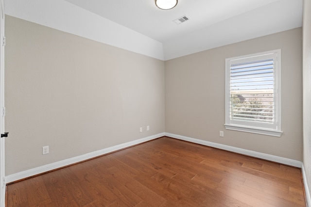 unfurnished room with wood finished floors, visible vents, and baseboards