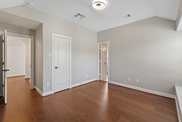 unfurnished bedroom featuring vaulted ceiling, visible vents, and wood finished floors