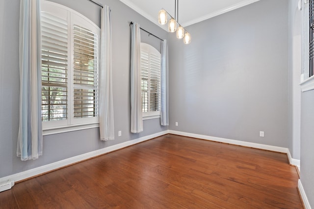 unfurnished room with crown molding, wood finished floors, baseboards, and a wealth of natural light