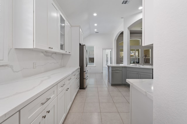 kitchen featuring glass insert cabinets, decorative backsplash, freestanding refrigerator, white cabinets, and a sink