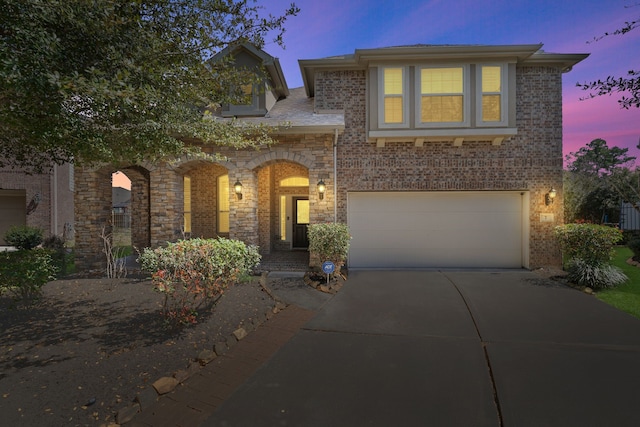 view of front of home featuring stone siding, an attached garage, brick siding, and driveway