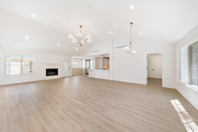 unfurnished living room featuring light wood-style flooring, a notable chandelier, and a large fireplace