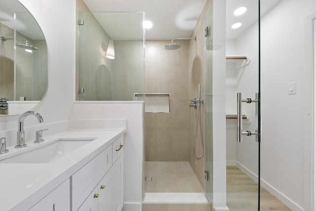 full bath with vanity, wood finished floors, baseboards, recessed lighting, and a stall shower