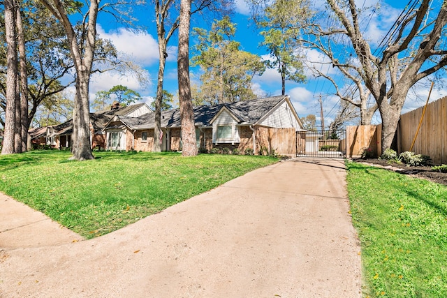 view of front of home with a gate, brick siding, a front lawn, and fence