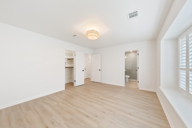 unfurnished bedroom featuring light wood finished floors, visible vents, and multiple windows