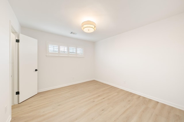 empty room with light wood-type flooring, visible vents, and baseboards