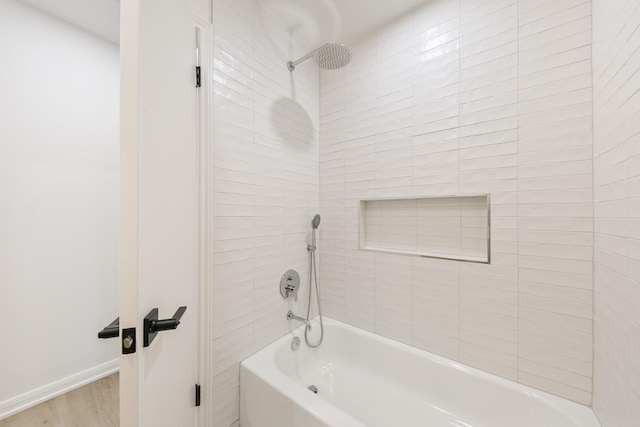 full bathroom featuring washtub / shower combination, wood finished floors, and baseboards