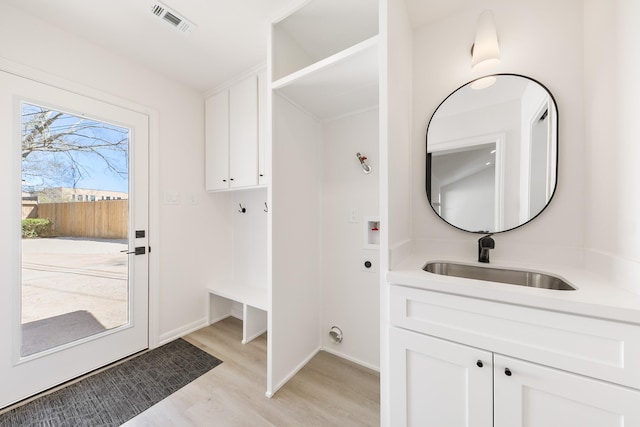 interior space featuring a sink, visible vents, baseboards, and light wood-style flooring