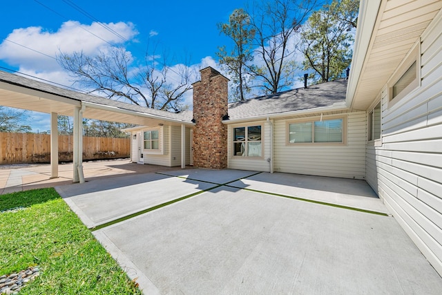 back of property featuring a patio area, fence, roof with shingles, and a chimney