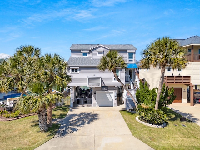 beach home featuring a gate, driveway, an attached garage, and stairs