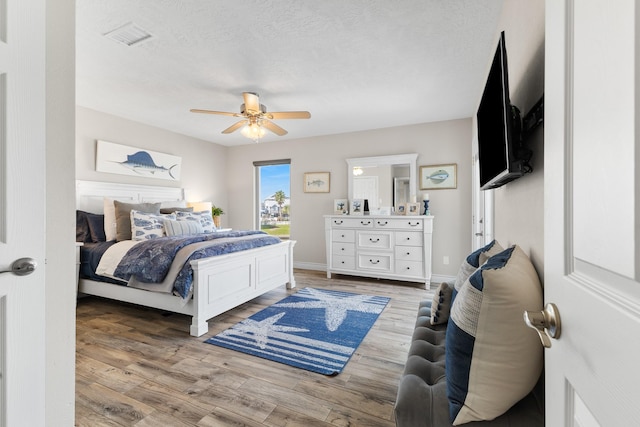 bedroom with a ceiling fan, baseboards, visible vents, and light wood finished floors