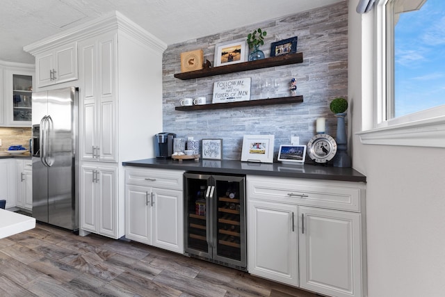 bar with dark wood-style floors, wine cooler, a dry bar, tasteful backsplash, and stainless steel fridge