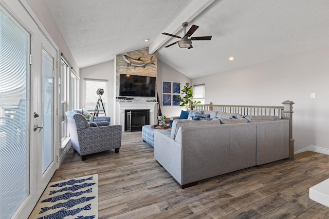 living room featuring lofted ceiling with beams, a large fireplace, baseboards, and wood finished floors