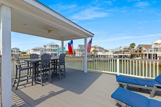 wooden deck with a water view, a residential view, and outdoor dining space