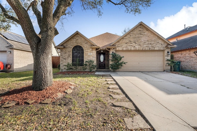 view of front of house featuring a garage, concrete driveway, brick siding, and roof with shingles