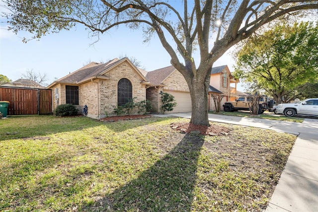 view of front of property featuring brick siding, an attached garage, a front yard, fence, and driveway